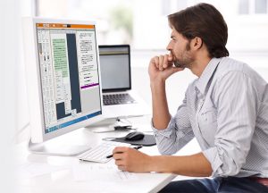 Image of man sitting in front of a desktop computer that has the FASTtrack software user interface on the screen.