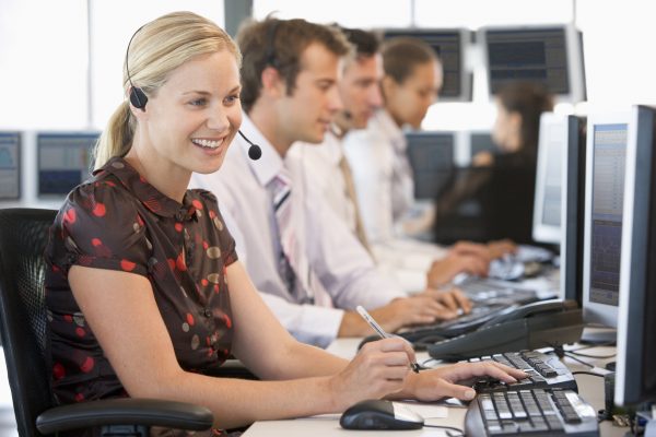 Image of call center staff lined up in front of their desktop computers answering customer inquiries