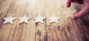 Image of stars lined up on a desk with a hand placing the last star on the right of the row depicting world class accessibility.