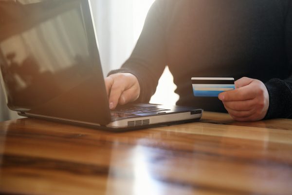 Image of a person entering sensitive subscriber data online with a credit card in hand