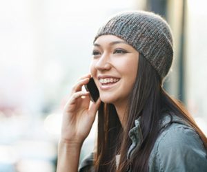 Image of woman smiling, talking on a mobile phone, representing customer activity in the telecommunications industry